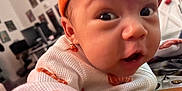 Nani joined the competition — help win amazing prizes! baby, blurred_background, child, close_up, cozy, curious_expression, cute, face, furniture, indoor, infant, knitted_clothing, open_mouth, orange_hat, person, portrait, wall_art, warm_colors, white_sweater, wide_eyes