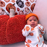 Nani joined the competition — help win amazing prizes! autumn, baby, background, cozy, cute, decor, face, fall, hat, indoors, infant, jack_o_lantern, onesie, orange, person, pillow, plush, pumpkin, sitting, white