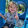 blue, child, curly_hair, daylight, finger_gesture, fun, greenery, happy, leisure, metal, outdoor, park, plastic, playground, shorts, slide, smiling, sunny, tshirt, youth