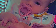 Nakyshia is registered to the contest to win money with this photo: baby, bib, child, closeup, clothing, curtain, cute, face, finger, hand, holding, indoor, infant, pacifier, person, portrait, skin, soft_light, window, young