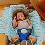 baby, newborn, sleeping, crochet, cowboy_hat, boots, basket, blanket, wooden_floor, indoor, hat, cozy, cute, infant, resting, hand, face, cactus, plant, decor