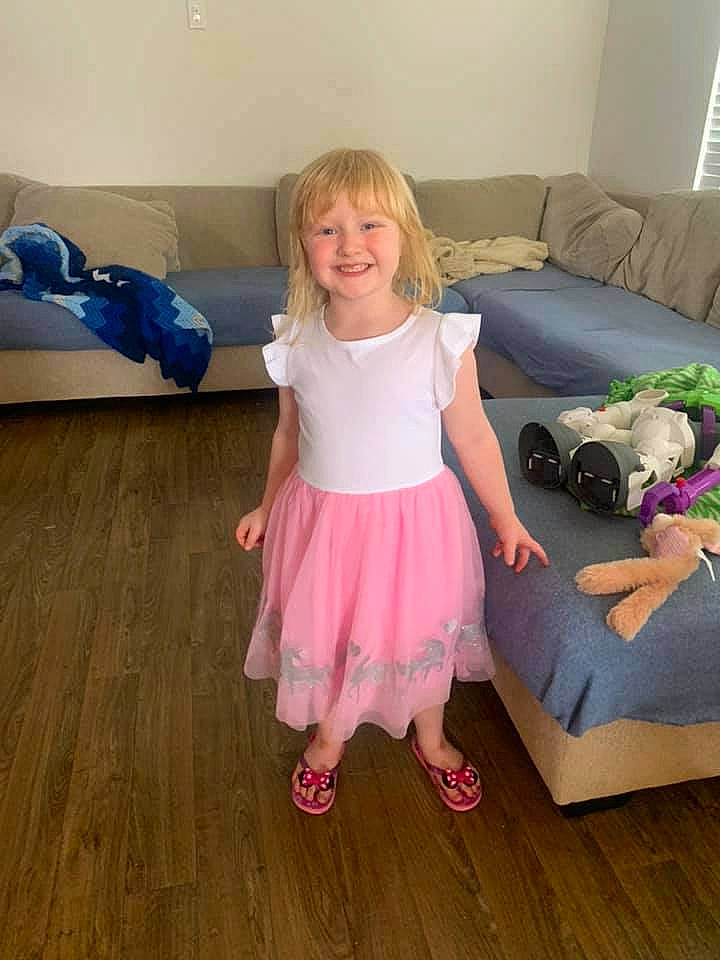 Saoirse is registered to the contest to win money with this photo: baby_toddler_clothing, child, comfort, couch, floor, flooring, fun, happy, hardwood, human_leg, joy, knee, magenta, person, pink, sitting, sleeve, smile, sock, studio_couch