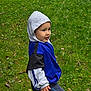 autumn_leaves, blue_clothing, casual_clothing, casual_wear, child, childhood, curious_expression, daylight, fall, grass, gray_clothing, greenery, hoodie, nature, outdoor, park, person, side_view, walking, young_boy