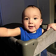 Alejandro joined the competition — help win amazing prizes! toddler, child, blue_shirt, playpen, indoor, curious, face, arm, expression, person, baby, furniture, home, lighting, portrait, young_child, smile, skin, hair, room