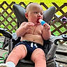 baby, child, popsicle, chair, porch, outdoor, grass, toys, trampoline, summer, greenery, wooden_floor, sock, clothing, face, expression, seat, fence, playtime, relaxation