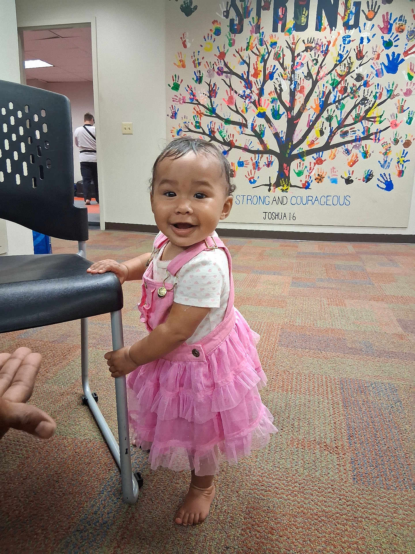 Xochitl Iv is registered to the contest to win money with this photo: toddler, child, pink_dress, barefoot, carpet, chair, handprint_mural, wall_art, indoor, smiling, happy, person, baby, standing, hand, colorful, decor, young_child, cute, portrait