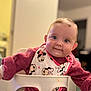 baby, infant, smile, high_chair, bib, clothing, indoor, child, cute, face, person, mickey_mouse, pink, red, sitting, young, portrait, happy, furniture, home