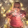 baby, infant, child, lights, string_lights, glowing, pink_clothing, blanket, happy, smiling, cute, indoor, soft_texture, playful, cozy, warm, face, hands, diaper, pajamas