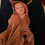 Alba participe au concours pour gagner de l'argent avec cette photo : baby, towel, hooded_towel, brown, blue_background, infant, face, eyes, cute, wrapped, blanket, newborn, child, skin, indoors, portrait, expression, laying, soft, ears