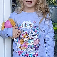 Mia a rejoint le concours — aidez-le/la à gagner de superbes lots ! child, blue_eyes, blonde_hair, pajamas, plush_toy, smiling, standing, outdoor, door, glass, cartoon_characters, purple_clothing, long_hair, happy, toy, person, cute, young, daylight, casual