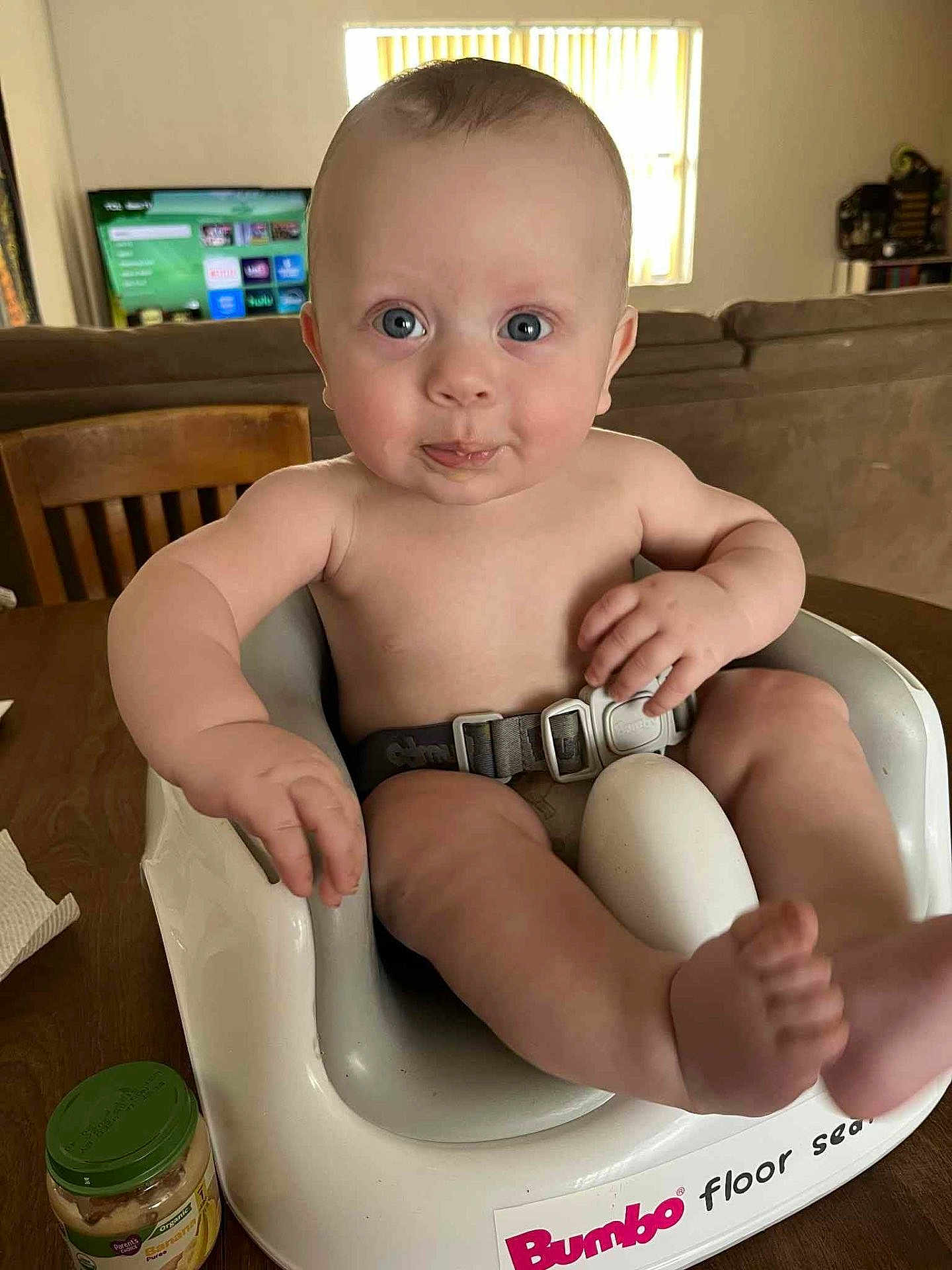 Wyatt joined the competition — help win amazing prizes! baby, infant, child, bumbo_seat, face, blue_eyes, table, wooden_chair, couch, indoor, baby_food, food_jar, person, skin, expression, seat, sitting, cute, funny_face, home