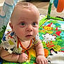 baby, infant, child, playmat, colorful, blue_eyes, curious, indoor, crawling, clothing, patterned_shirt, hands, face, head, floor, toy, animal_prints, closeup, person, young
