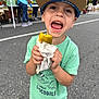 Ashtyn joined the competition — help win amazing prizes! child, boy, pickle, food, cap, green_shirt, smiling, outdoor, street, people, event, happy, casual_clothing, daytime, holding, young, fun, playful, person, celebration