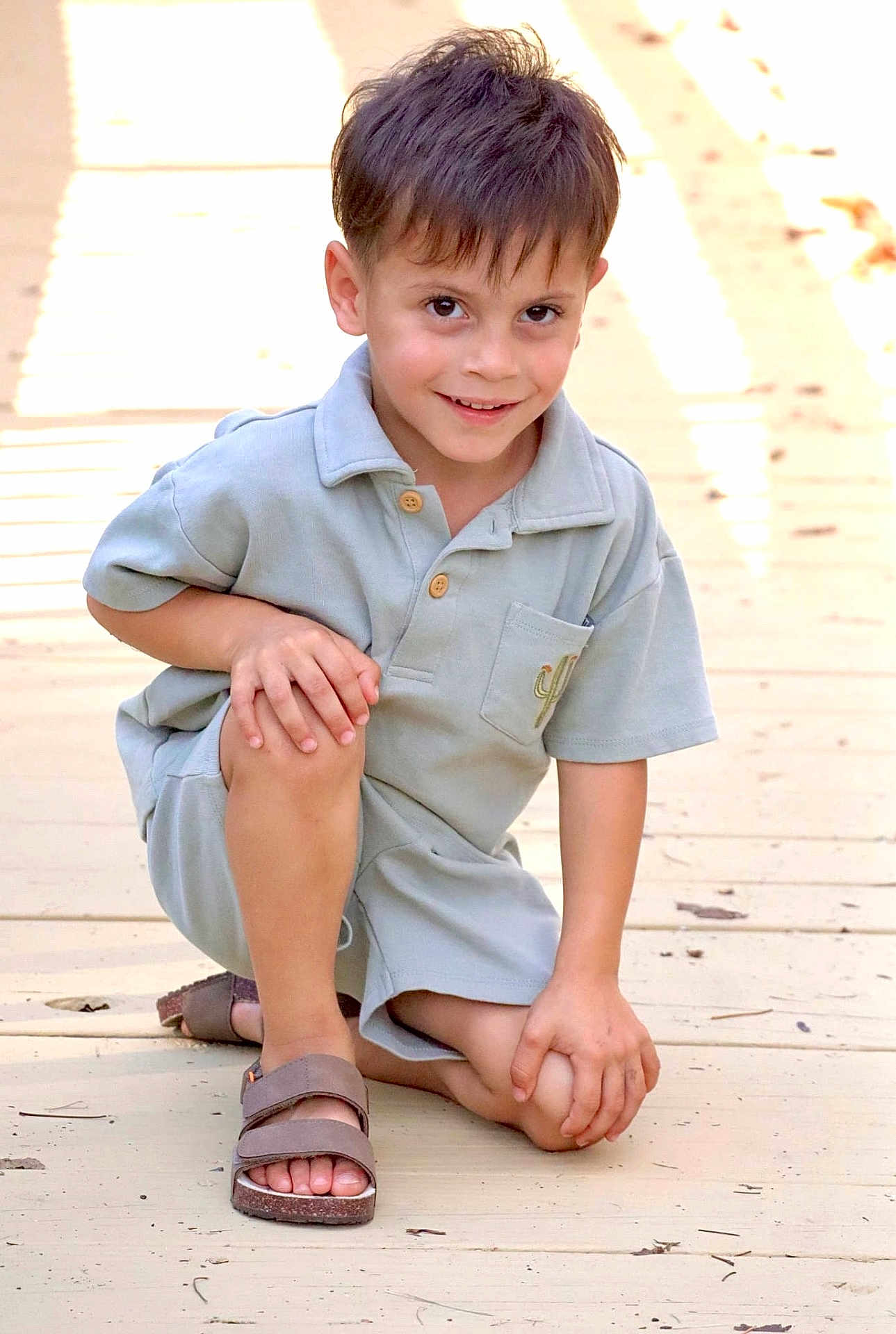 Ashtyn joined the competition — help win amazing prizes! child, boy, smiling, outdoor, sandals, wooden_floor, sunlight, shorts, shirt, happy, crouching, portrait, casual_clothing, young, daylight, skin, feet, hair, person, cute