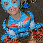 Ashtyn joined the competition — help win amazing prizes! barefoot, blue, brown, captain_america, carpet, cat, child, costume, cute, furniture, happy, indoor, mask, person, playful, red, room, sitting, smile, toy_truck