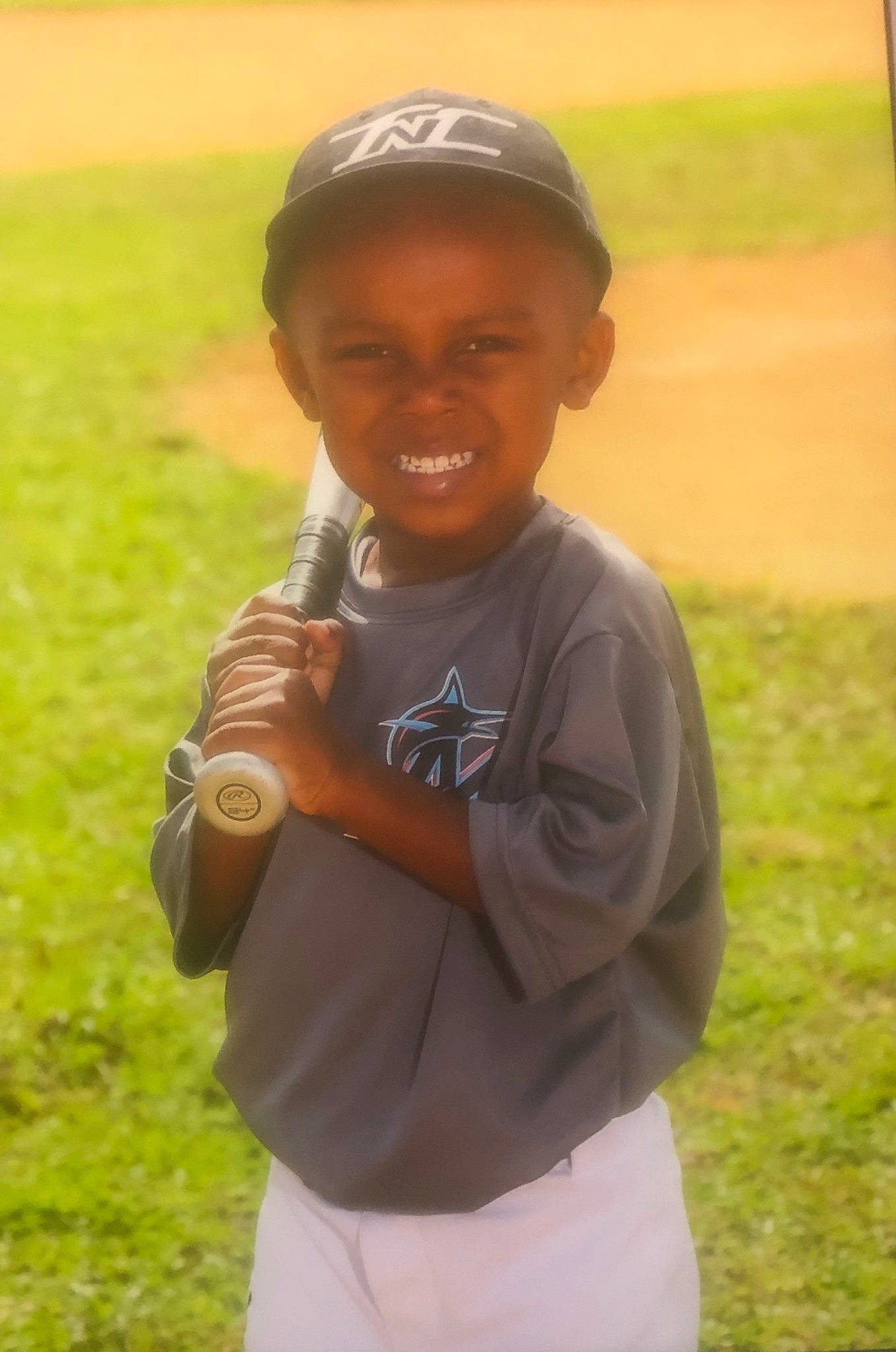 Aydin is registered to the contest to win money with this photo: baseball, baseball_glove, baseball_player, child, grass, joy, person, smile