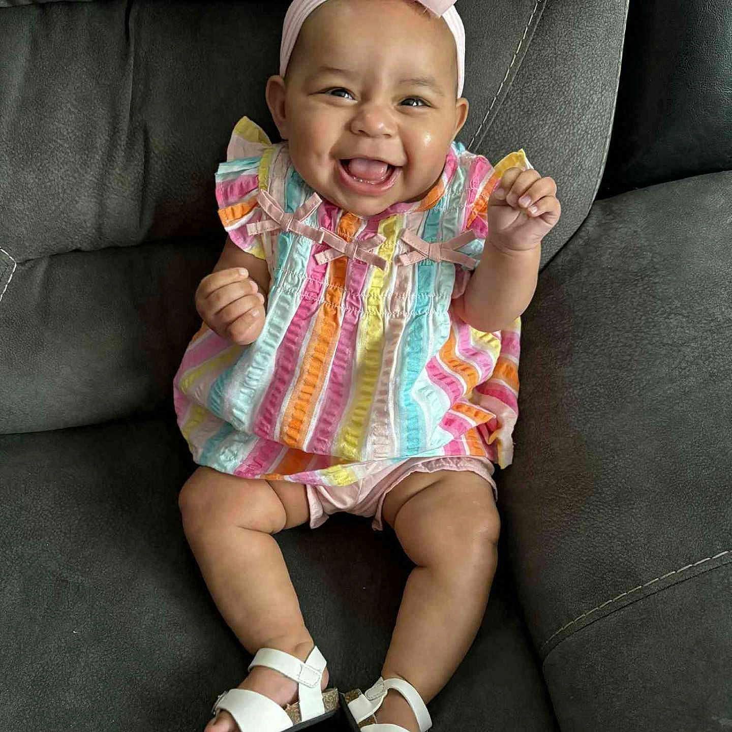 Samaria joined the competition — help win amazing prizes! baby, child, colorful, couch, cute, dress, flower, footwear, happy, headband, indoor, infant, joyful, person, pink, portrait, sandals, sitting, smiling, striped