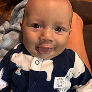 Liam joined the competition — help win amazing prizes! baby, blanket, child, close_up, clothing, drool, eyes, face, family_snapshot, happy, indoor, infant, navy_blue, onesie, portrait, sitting, smiling, tongue, warm_lighting, white