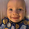Liam joined the competition — help win amazing prizes! adorable, baby, bedding, blue_clothing, camera, child, close_up, clothing, cozy, eyes, face, grinning, happy, head, indoor, infant, patterned_outfit, portrait, smiling, warm_lighting