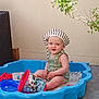 Côme a rejoint le concours — aidez-le/la à gagner de superbes lots ! baby, child, sandbox, blue, hat, striped, green_clothing, toys, sand, outdoor, plant, branch, floor, smiling, sitting, happy, face, headwear, play, toddler