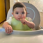 Kaïs a rejoint le concours — aidez-le/la à gagner de superbes lots ! baby, bib, child, curious, cute, eating, face, food, furniture, hand, high_chair, indoor, infant, kitchen, munching, person, snack, table, tile_wall, young_child