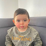 Kaïs participe au concours pour gagner de l'argent avec cette photo : baby, child, face, person, sitting, sweatshirt, clothing, lion_king, disney, couch, indoor, cute, expression, young_child, portrait, hands, hair, eyebrows, eyes, skin