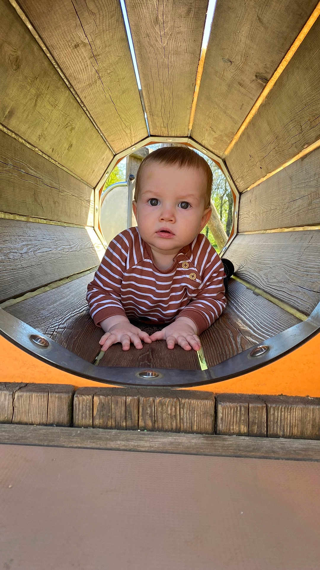 Cristian a rejoint le concours — aidez-le/la à gagner de superbes lots ! baby, child, striped_shirt, wood, playground, tunnel, crawling, outdoor, daylight, curious, face, hands, wooden_tunnel, natural_light, young_child, person, play, cute, expression, casual_clothing