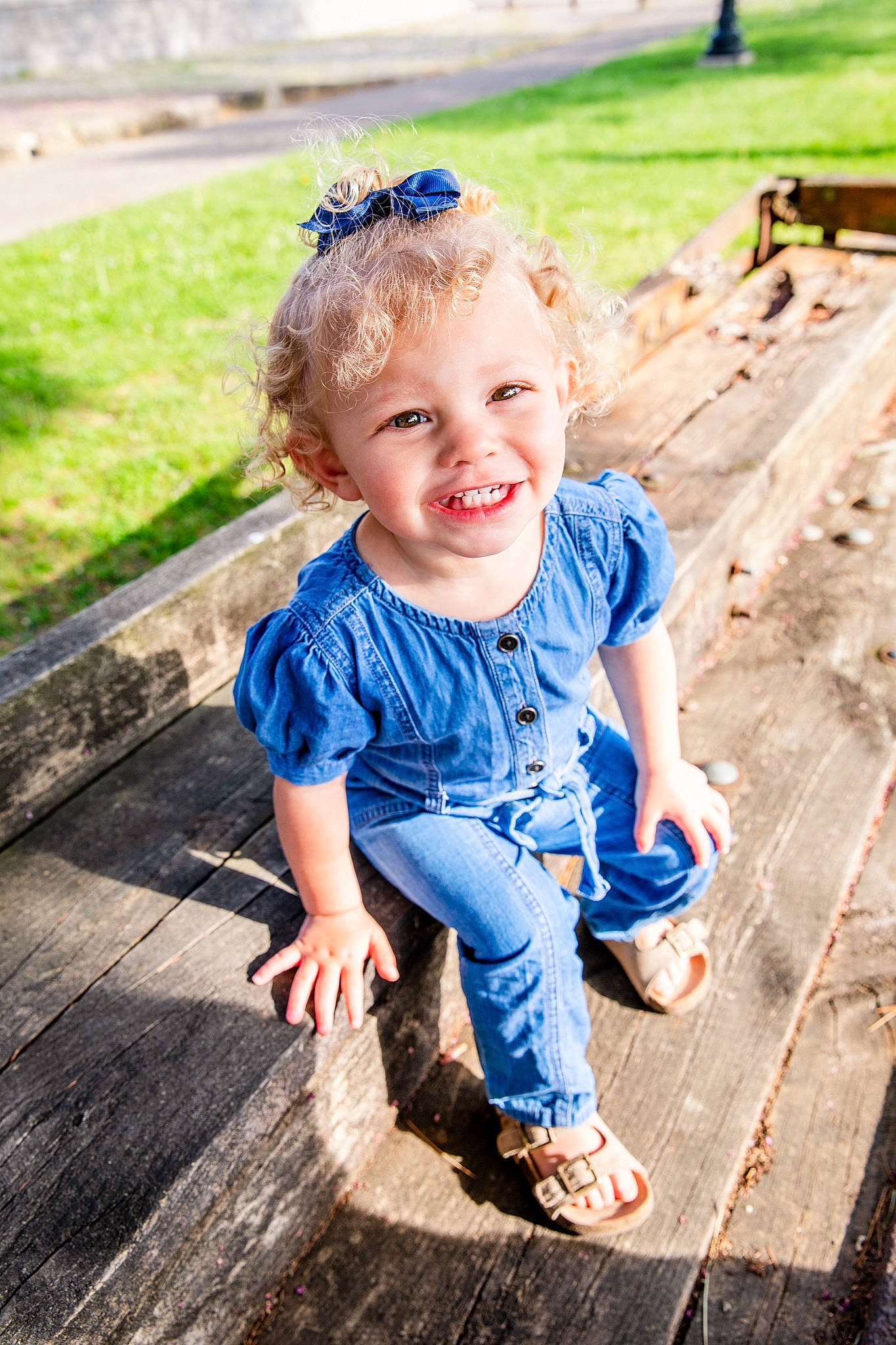 Anya is registered to the contest to win money with this photo: azure, baby_toddler_clothing, blue, eye, facial_expression, grass, hairstyle, hand, happy, joy, leaf, leisure, people_in_nature, person, photograph, plant, skin, smile, standing, toddler
