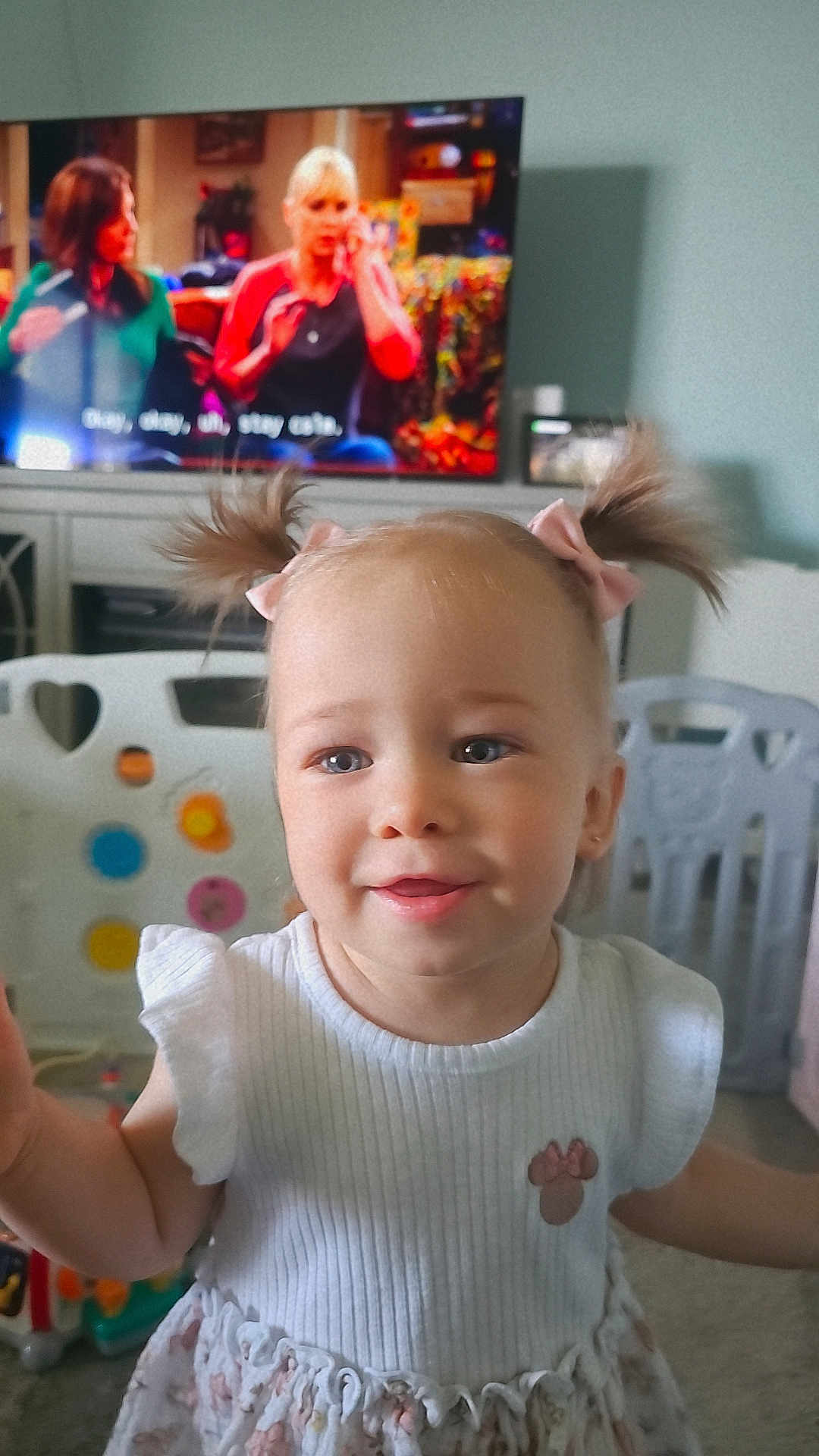 Alana joined the competition — help win amazing prizes! toddler, child, girl, pigtails, pink_bows, white_dress, smile, indoor, toys, television, furniture, play_area, face, person, cute, home, happy, young_child, room, background