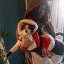 Angela joined the competition — help win amazing prizes! animal, cat, christmas, costume, cozy, cute, decor, face, festive, fur, holding, holiday, indoor, long_hair, person, pet, plant, reindeer_onesie, santa_outfit, window