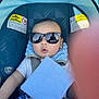 baby, child, car_seat, sunglasses, seatbelt, blanket, clothing, infant, child_seat, safety, cute, face, expression, indoor, photography, text_label, warning_sign, finger, hand, accessory