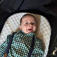 Arthur joined the competition — help win amazing prizes! baby, infant, smiling, face, green_checkered_shirt, suspenders, cushion, stroller, happy, child, young, clothing, head, person, portrait, indoor, cute, baby_boy, lying_down, comfortable