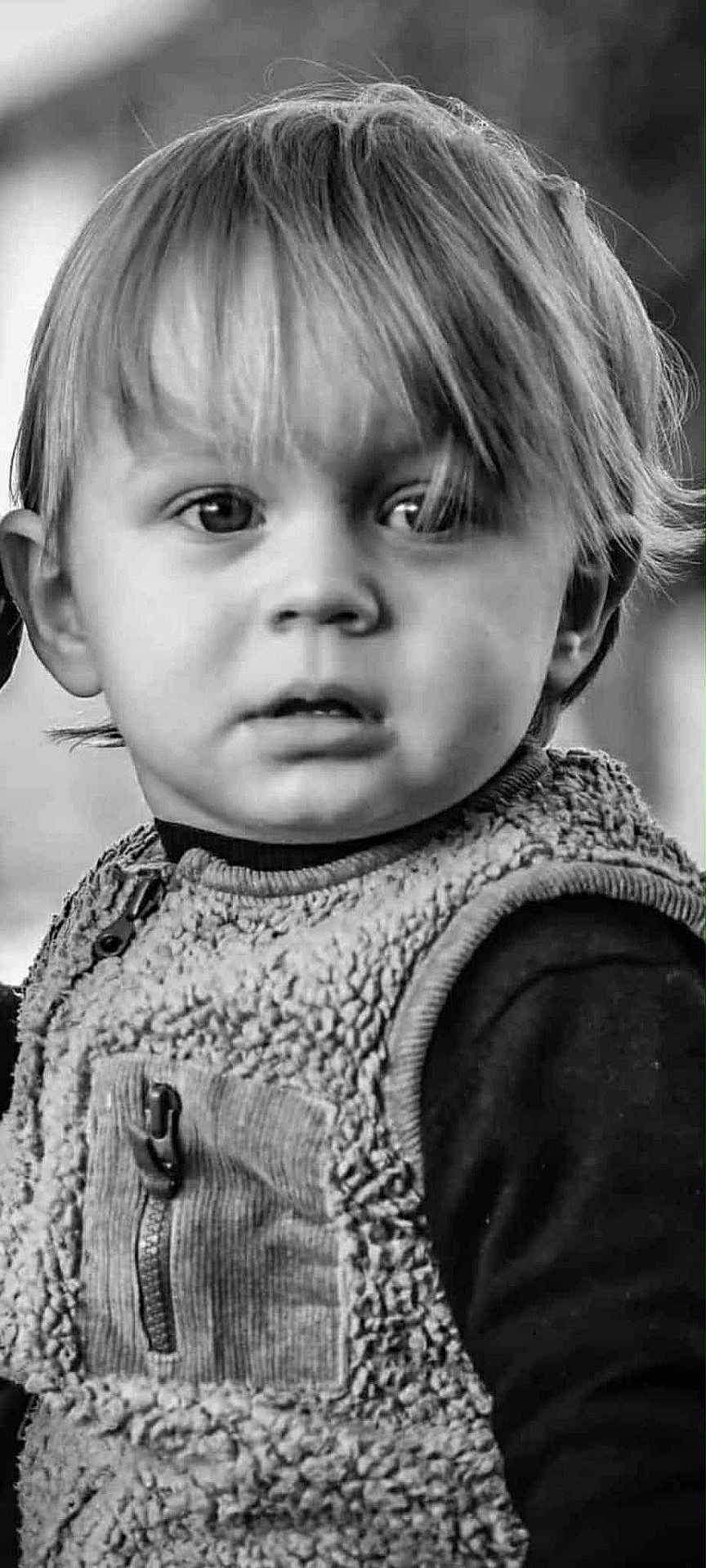 Jean participe au concours pour gagner de l'argent avec cette photo : toddler, child, face, portrait, black_and_white, curly_hair, vest, clothing, expression, young_child, person, closeup, eyes, hair, innocence, cute, texture, warm_clothing, outdoor, curiosity