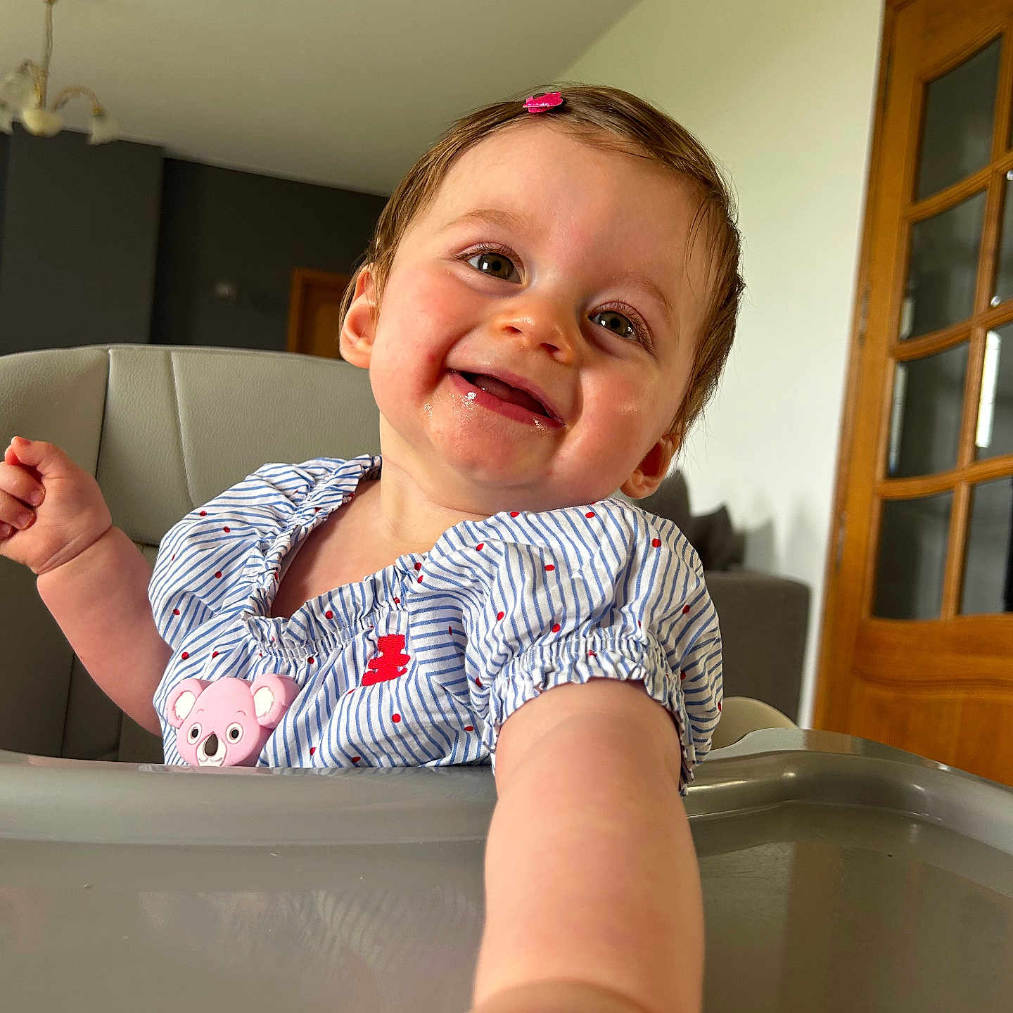 Livia participe au concours pour gagner de l'argent avec cette photo : arm, baby, cheek, child, clothing, couch, eyes, face, hair_clip, happy, high_chair, indoor, light, person, room, skin, smile, table, window, wooden_door