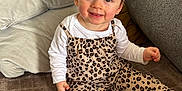 Livia a rejoint le concours — aidez-le/la à gagner de superbes lots ! baby, casual, child, clothing, couch, cute, face, hair_clips, happy, home, indoor, leopard_print, overalls, person, pillows, sitting, smiling, toddler, white_socks, young_child