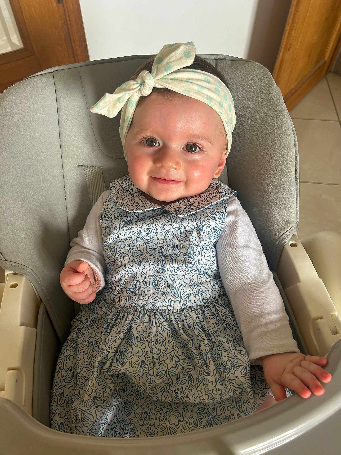 Livia participe au concours pour gagner de l'argent avec cette photo : baby, child, girl, smile, headband, polka_dot, dress, floral_pattern, high_chair, indoor, person, hand, face, long_sleeve, seated, cute, happy, skin, wooden_door, tile_floor