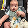 baby, infant, car_seat, plush_toy, bib, onesie, dinosaur_pattern, child, cute, soft_toy, indoor, portrait, face, chubby_cheeks, sitting, looking_at_camera, clothing, person, young_child, expression