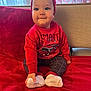 Thomas participe au concours pour gagner de l'argent avec cette photo : baby, child, red_sweater, hat, socks, couch, indoor, portrait, cute, smiling, face, person, window, curtains, plaid_pants, hand, seated, cozy, home, soft_fabric