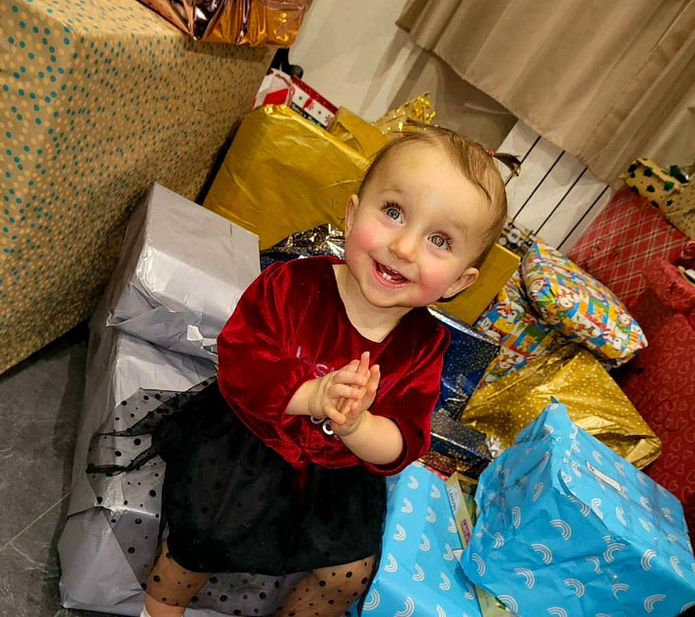 Elya a rejoint le concours — aidez-le/la à gagner de superbes lots ! child, christmas, comfort, couch, event, flooring, fun, happy, holiday, joy, kimono, lap, living_room, person, pillow, play, room, sitting, sleeve, smile