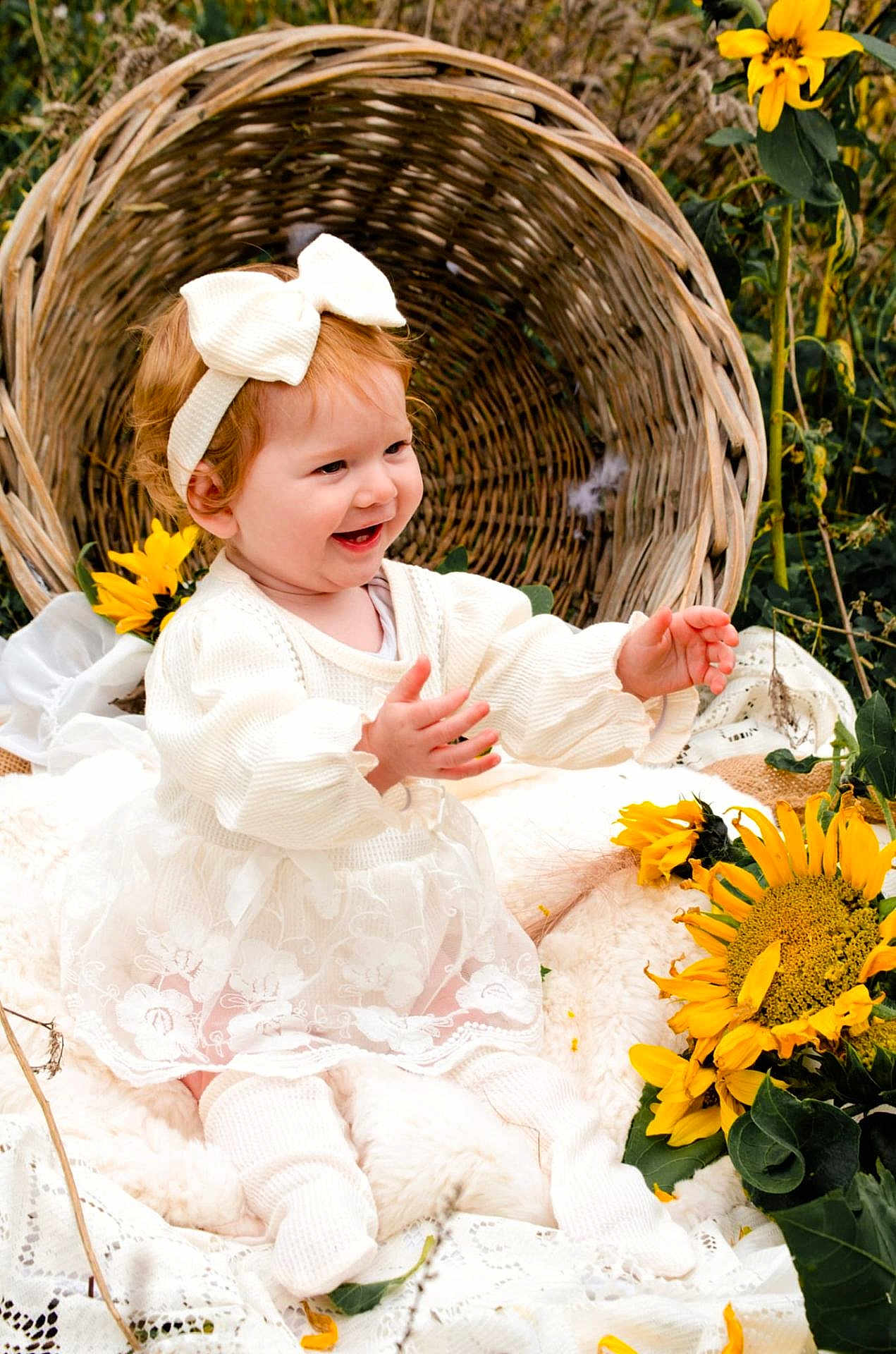Kelsy a rejoint le concours — aidez-le/la à gagner de superbes lots ! baby, child, smiling, white_dress, headband, sunflowers, basket, blanket, outdoor, grass, nature, happy, cute, portrait, sitting, flower, infant, warm, daylight, pretty