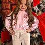 child, girl, smile, long_hair, hoodie, sweatpants, christmas_tree, holiday, decorations, red_bow, ornaments, indoor, portrait, festive, happy, pose, winter_clothing, bright, celebration, home
