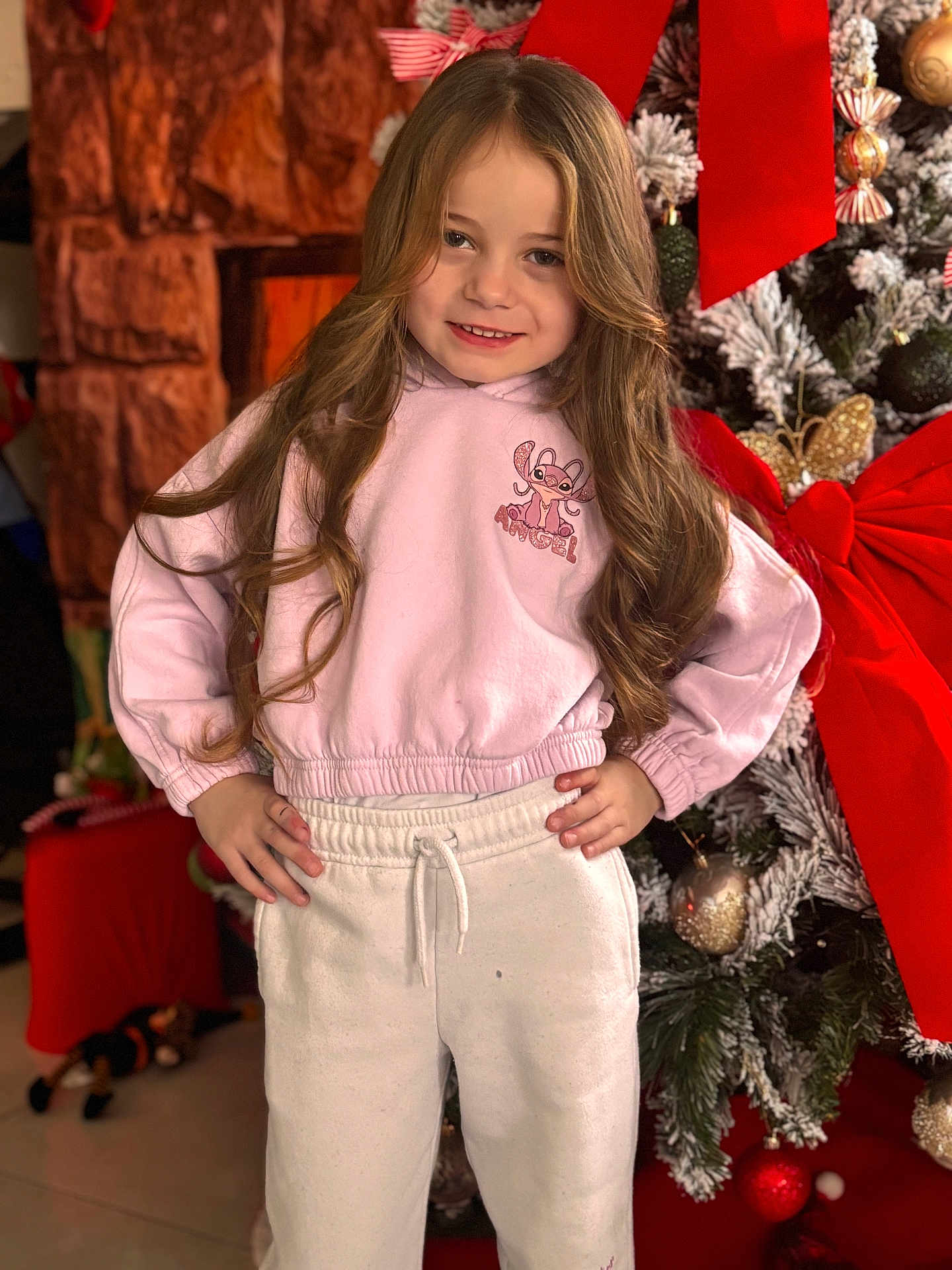 Ruby participe au concours pour gagner de l'argent avec cette photo : child, girl, smile, long_hair, hoodie, sweatpants, christmas_tree, holiday, decorations, red_bow, ornaments, indoor, portrait, festive, happy, pose, winter_clothing, bright, celebration, home