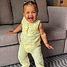 Gia Elora joined the competition — help win amazing prizes! toddler, child, smiling, standing, yellow_outfit, hair_buns, indoor, couch, carpet, sandals, happy, person, home, patterned_rug, baby, cute, joyful, furniture, portrait, playful