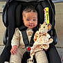 baby, beige_clothing, black_car_seat, car_seat, car_seat_harness, child, cute, drool, floor, happy, indoors, infant, knitwear, lion_toy, person, plush_toy, seatbelt, smiling, soft_toy, toddler