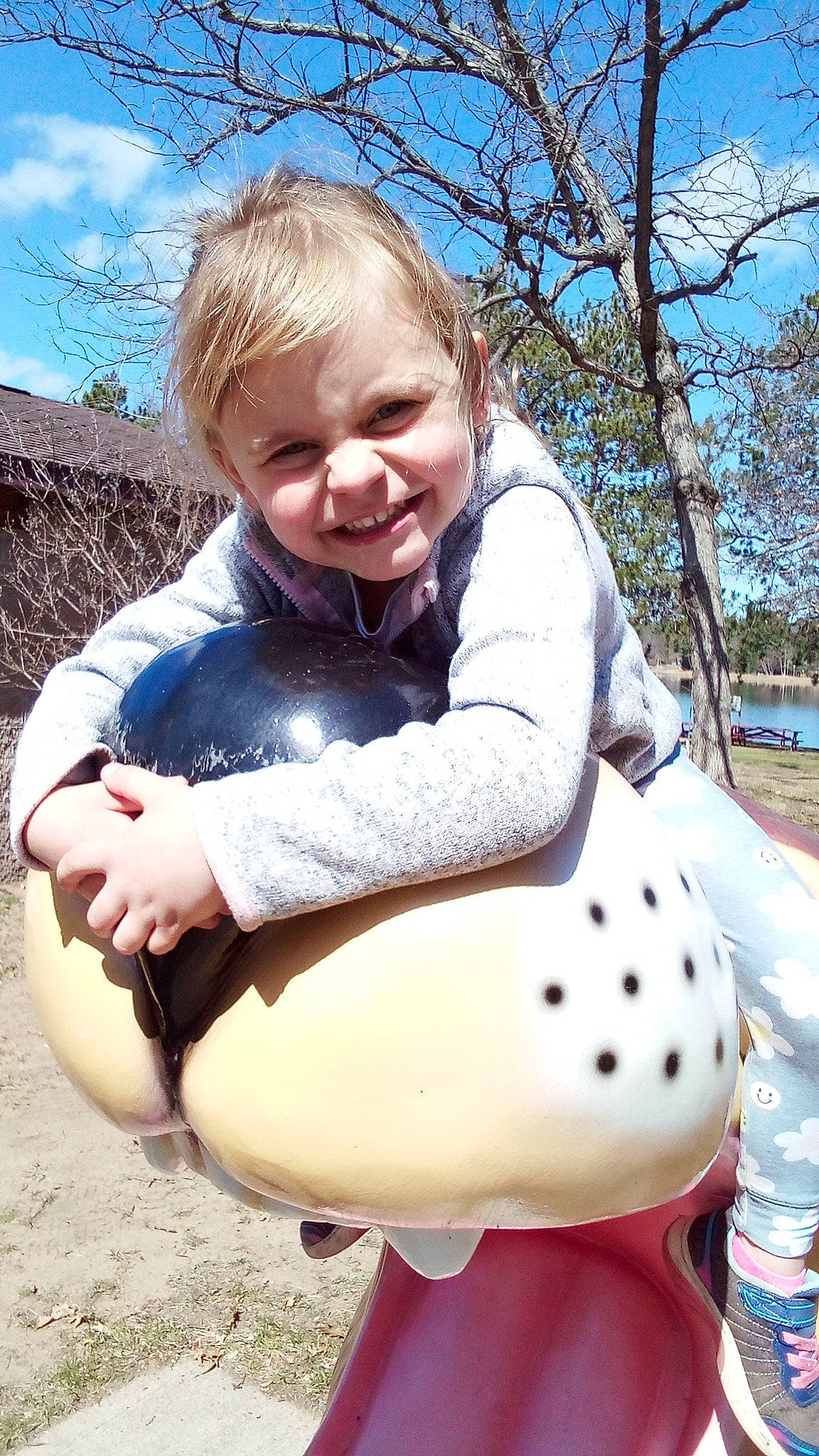 Melody joined the competition — help win amazing prizes! child, facial_expression, fun, grass, happy, human_leg, joy, knee, leisure, outdoor_play_equipment, people_in_nature, person, play, recreation, sitting, sky, smile, thigh, toddler, toy