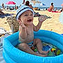 baby, child, beach, sand, inflatable_pool, water, hat, bucket_hat, smiling, happy, summer, sunny, umbrella, toys, play, vacation, outdoor, sea, people, relax