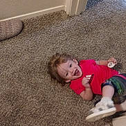 Aspen is registered to the contest to win money with this photo: toddler, child, carpet, floor, doorway, pacifier, baby_bottle, slipper, red_shirt, colorful_pants, smiling, happy, indoors, person, footwear, toy, candid, playful, young_child, home