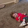 toddler, child, carpet, floor, doorway, pacifier, baby_bottle, slipper, red_shirt, colorful_pants, smiling, happy, indoors, person, footwear, toy, candid, playful, young_child, home
