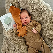 Marcelin a rejoint le concours — aidez-le/la à gagner de superbes lots ! baby, infant, plush_toy, blanket, milestone_card, brown_clothing, socks, cute, lying_down, face, expression, soft_texture, indoor, newborn, child, portrait, cozy, small_hands, fur_texture, floor