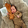 baby, infant, plush_toy, blanket, milestone_card, brown_clothing, socks, cute, lying_down, face, expression, soft_texture, indoor, newborn, child, portrait, cozy, small_hands, fur_texture, floor